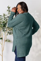 Woman modeling a ribbed teal long sleeve sweater and dark jeans, smiling indoors