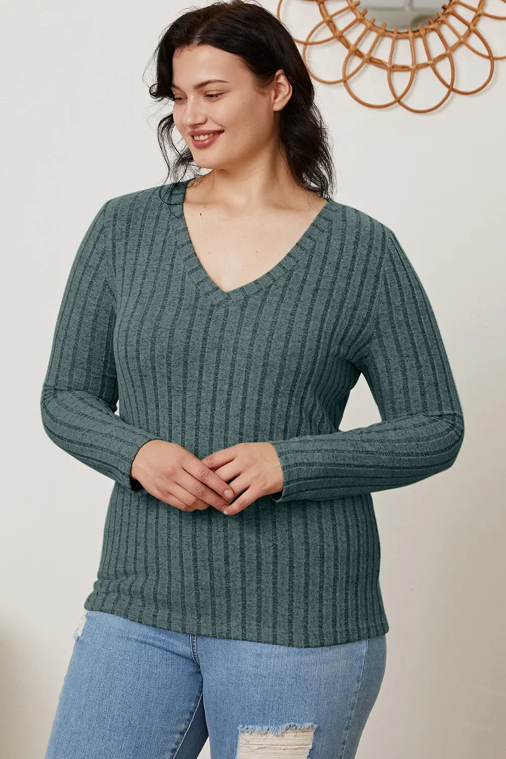 Woman wearing a ribbed, long-sleeve V-neck sweater with distressed jeans