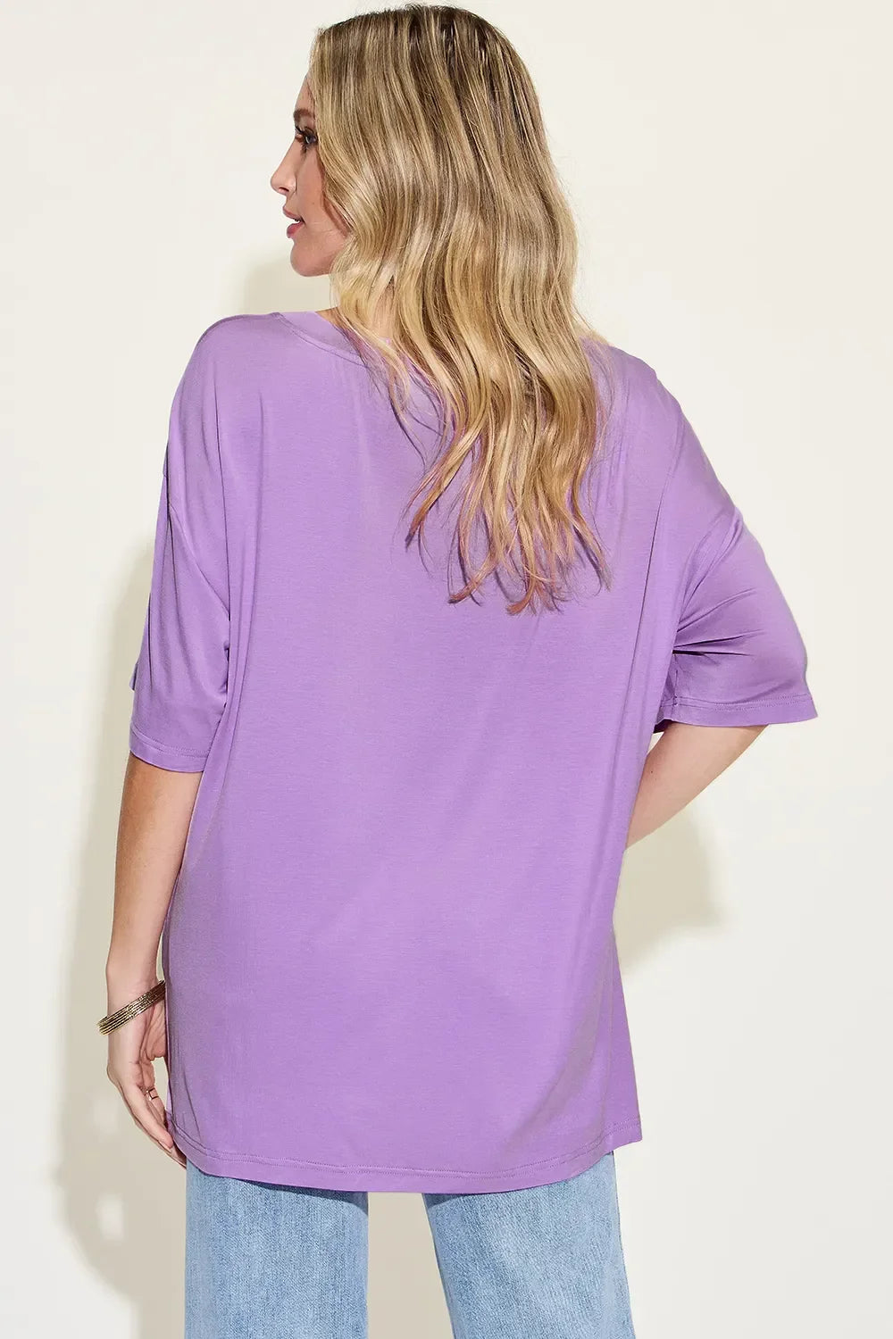 Woman wearing a loose lavender t-shirt and light blue jeans, shown from the back.