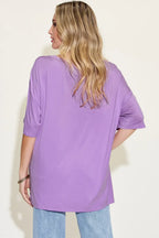 Woman wearing a loose lavender t-shirt and light blue jeans, shown from the back.