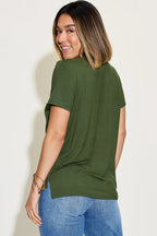 Woman in an olive green short sleeve t-shirt and blue jeans smiling, back view