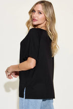 Woman modeling loose black short sleeve t-shirt with light blue jeans, side view