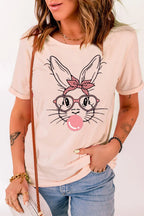 Woman wearing a light pink t-shirt with a cute bunny face, glasses, bandana, and bubble gum print.