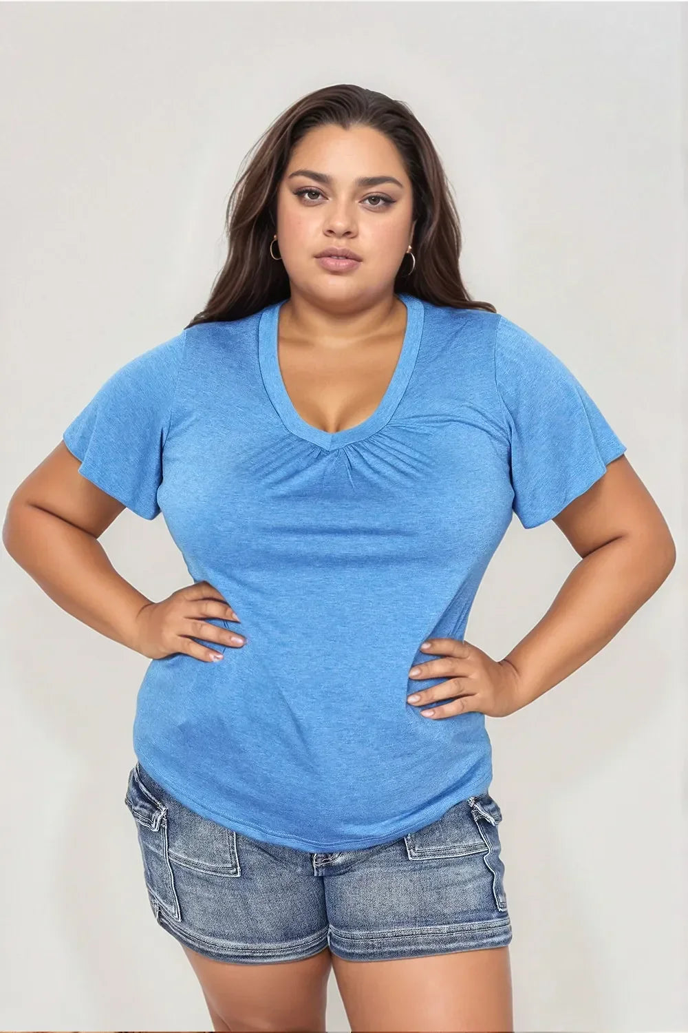 Woman modeling a blue V-neck short sleeve top and denim shorts, casual plus size outfit