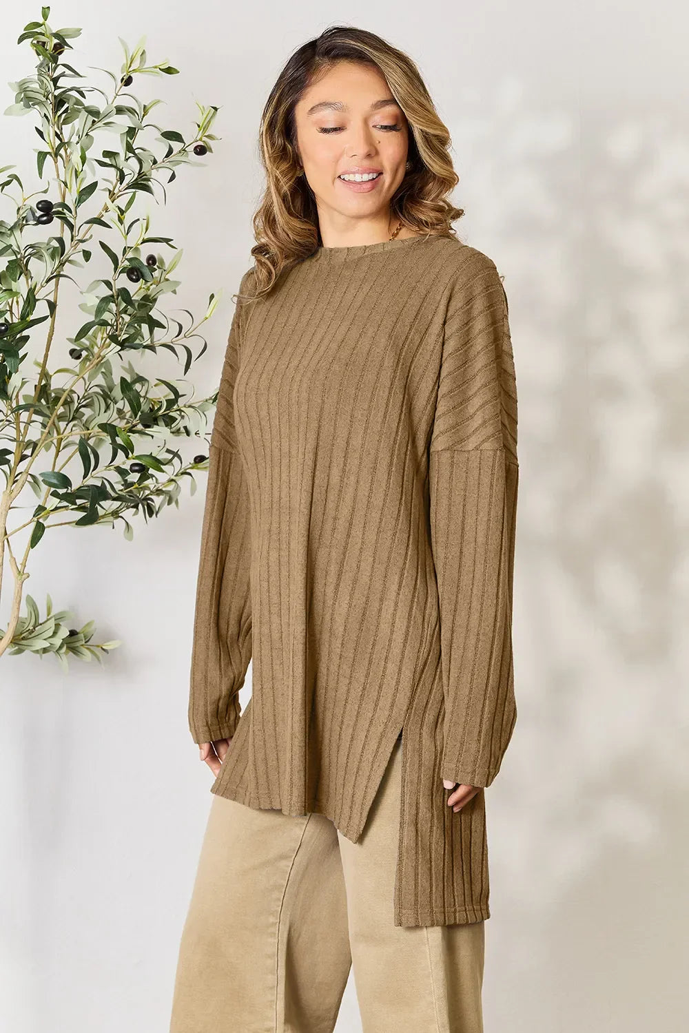 Woman wearing a ribbed, long sleeve brown knit sweater tunic and beige pants