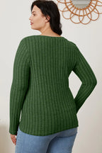 Woman wearing a long sleeve green ribbed knit sweater and light blue jeans