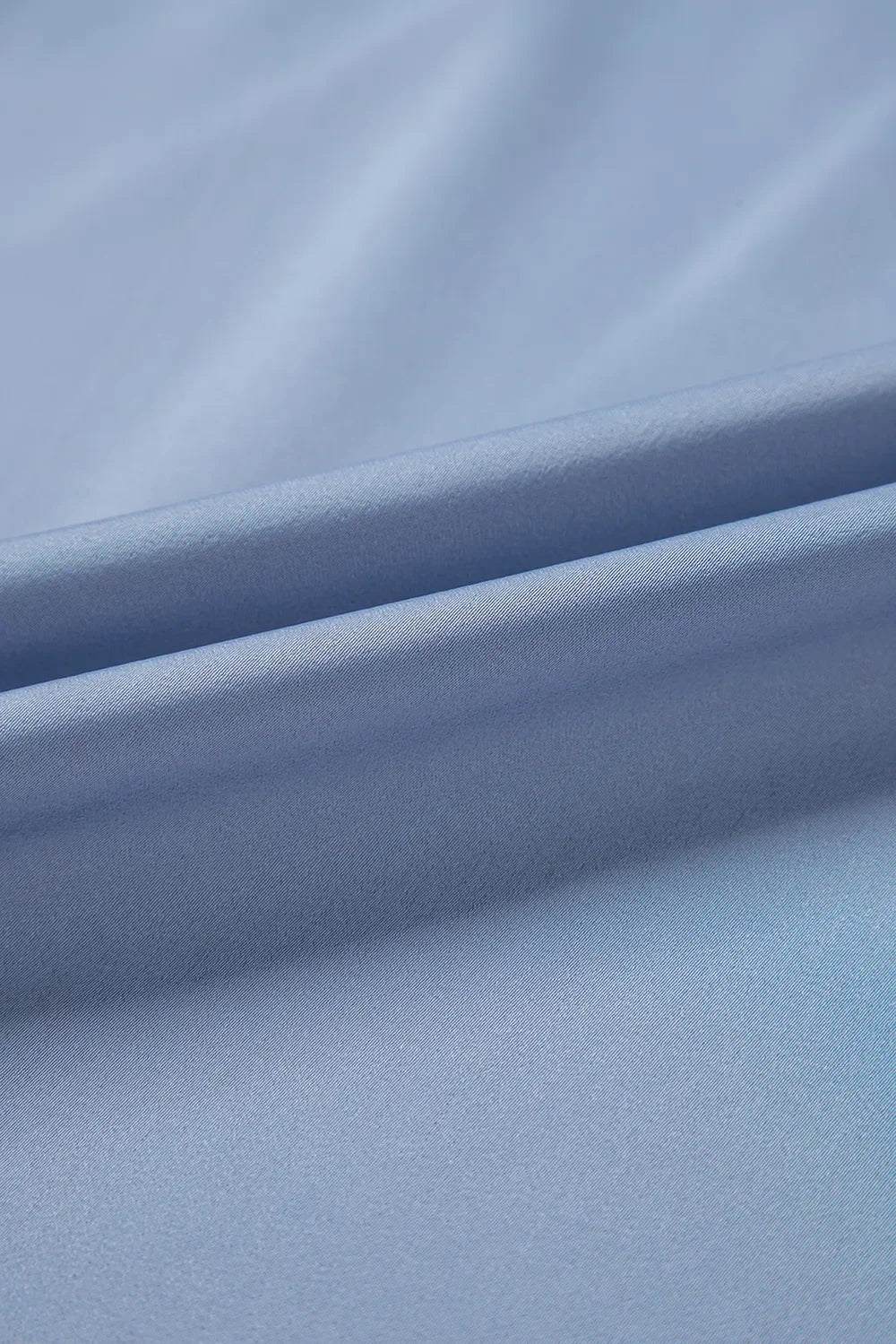 Close-up of smooth light blue fabric with soft folds, ideal for stylish clothing or accessories