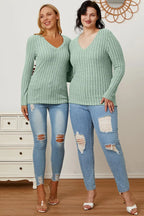 Two women in mint green ribbed sweaters and ripped blue skinny jeans, standing indoors