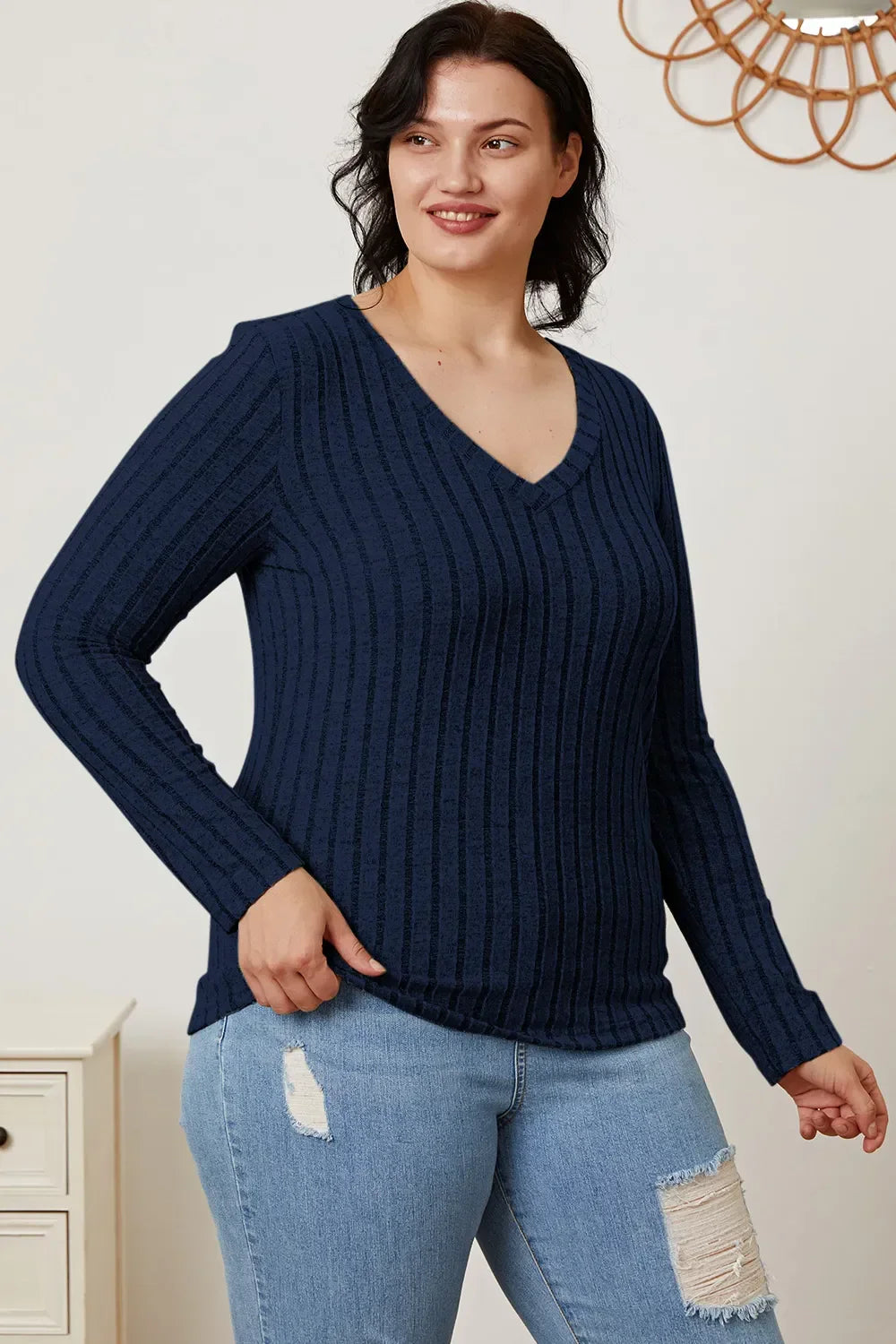Woman in navy blue ribbed knit V-neck sweater and distressed light blue jeans