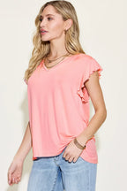 Woman wearing pink ruffle sleeve V-neck top with blue jeans, casual fashion outfit