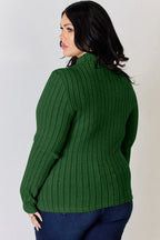 Woman wearing a ribbed green long sleeve sweater and blue jeans, side view