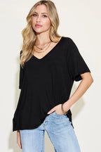Woman wearing a loose black V-neck short sleeve top with light blue jeans and layered gold jewelry