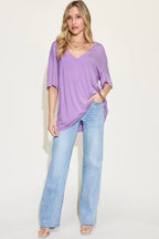 Woman wearing a loose lavender V-neck top with light blue wide-leg jeans and sandals
