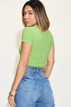 Woman wearing a green ribbed short sleeve top and high-waisted blue jeans