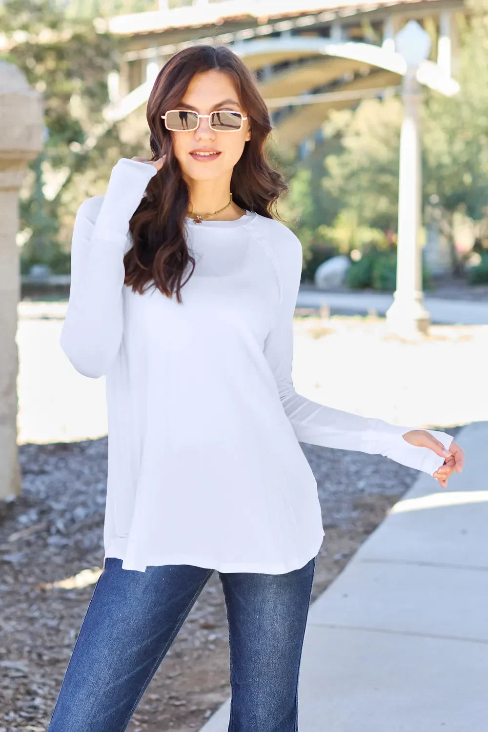 Woman wearing a white long sleeve top and blue jeans outdoors
