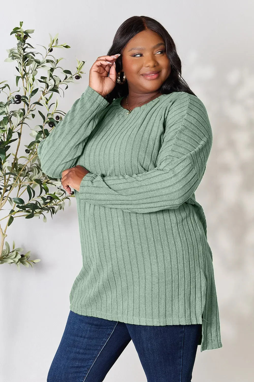 Woman wearing sage green ribbed knit long sleeve sweater with blue jeans