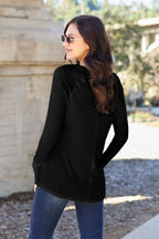 Woman in black long sleeve top and blue jeans outdoors, wearing sunglasses