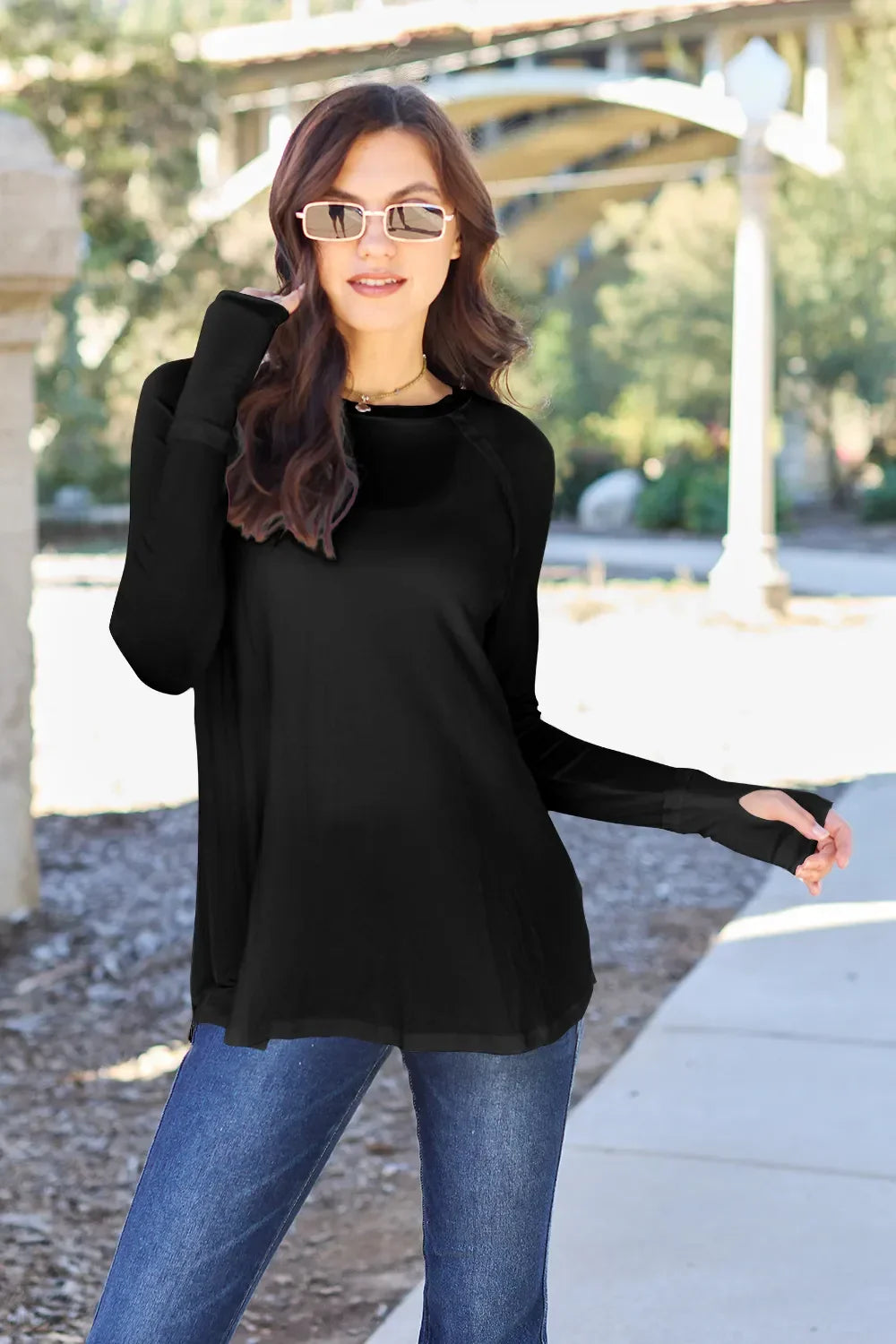 Woman in black long sleeve top and jeans wearing sunglasses outdoors