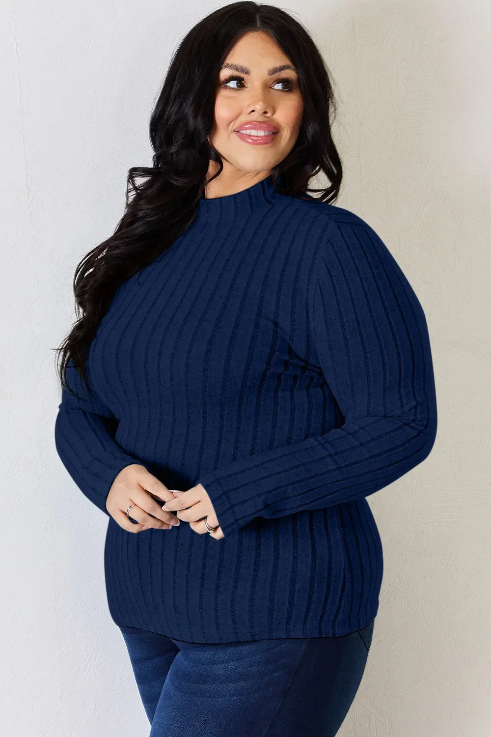 Woman wearing a navy blue ribbed knit long sleeve sweater and dark jeans