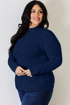 Woman wearing a navy blue ribbed knit long sleeve sweater and dark jeans