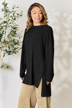 Woman wearing a black ribbed long sweater with side slits and beige pants, casual fashion