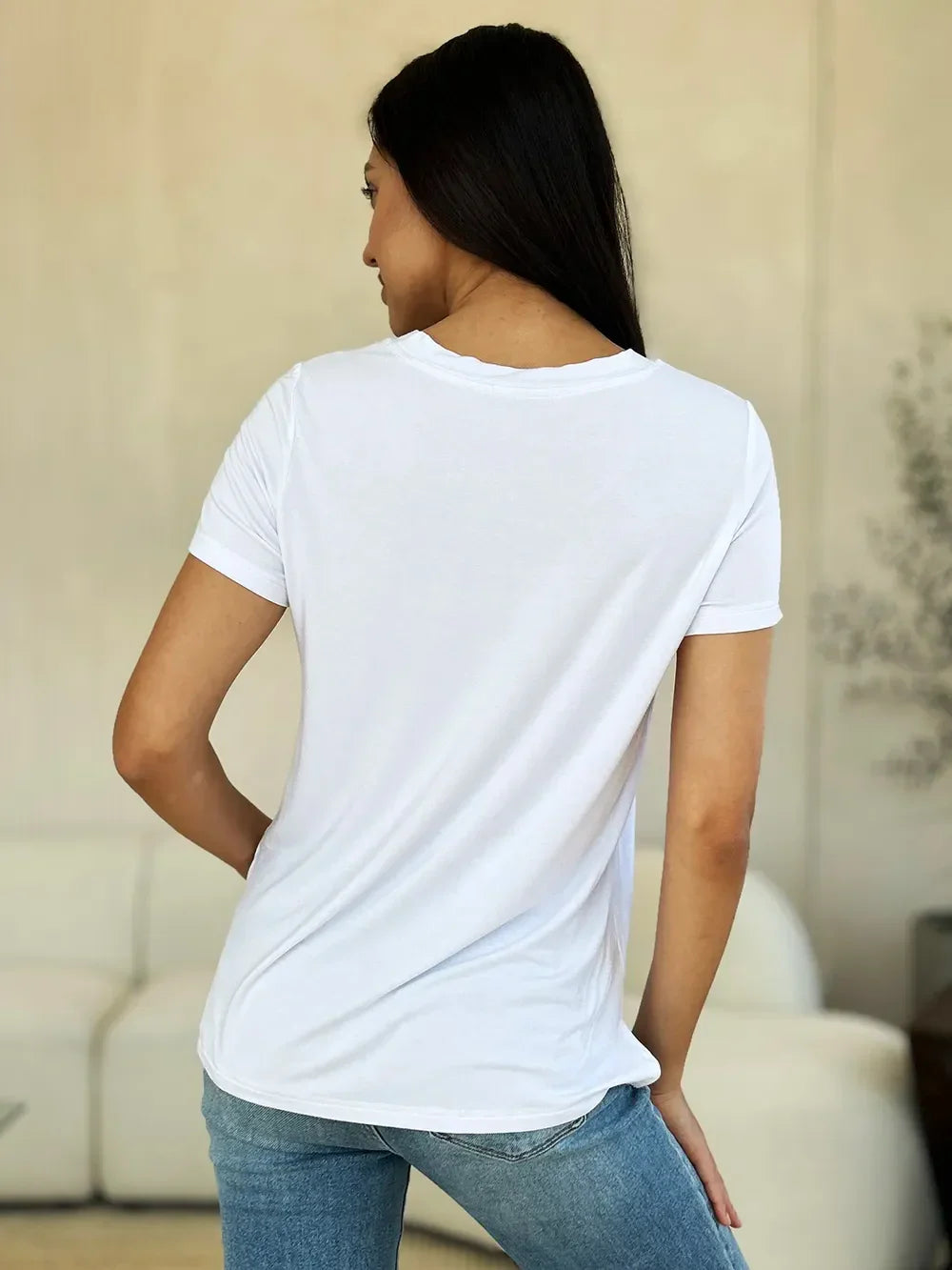 Woman wearing plain white t-shirt and blue jeans, back view, casual outfit indoors