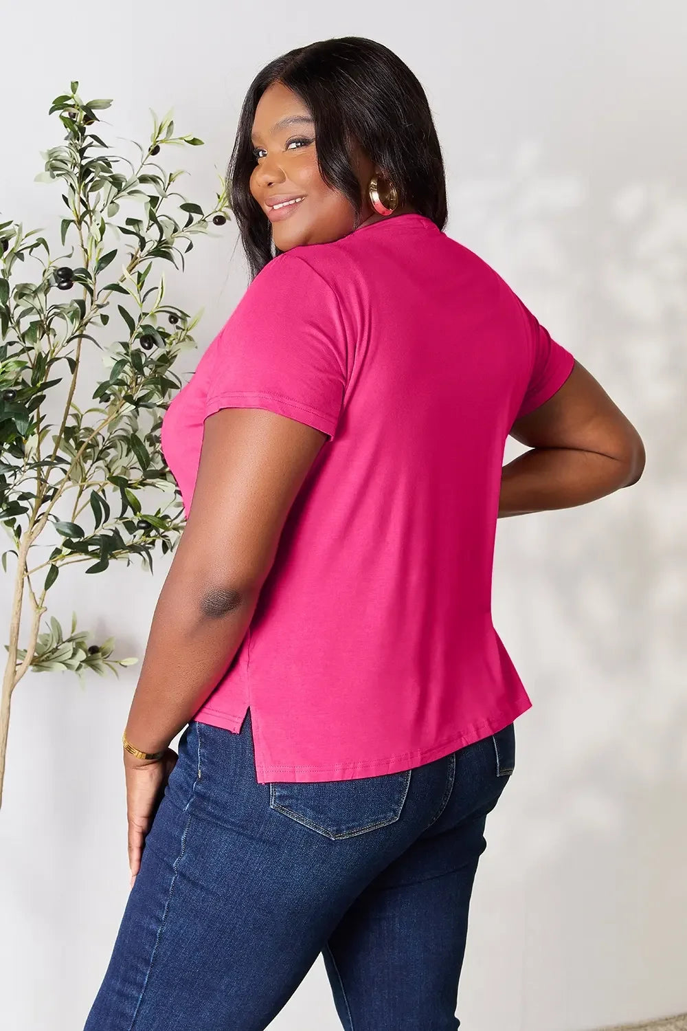 Woman in casual hot pink T-shirt and blue jeans, smiling, indoor fashion photo