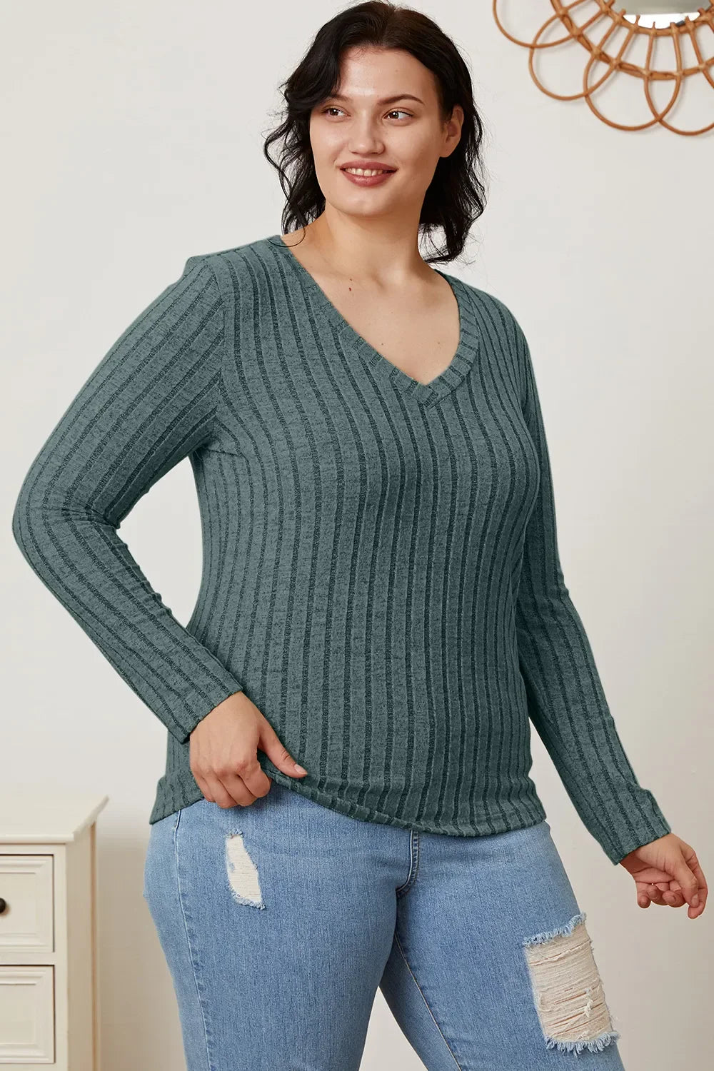 Woman in a ribbed long sleeve V-neck sweater and distressed blue jeans