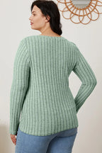 Woman wearing light green ribbed knit sweater with long sleeves and blue jeans, back view