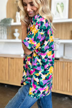 Woman wearing colorful abstract print short sleeve top and blue jeans indoors