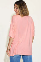 Woman in loose pink t-shirt and blue jeans, back view, casual outfit style