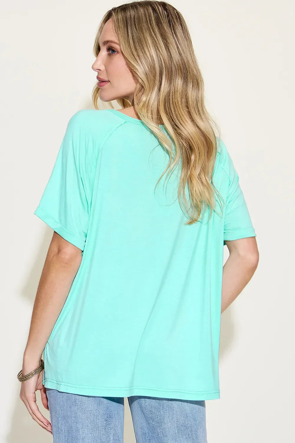 Woman in mint green short sleeve top and light blue jeans, shown from the back.