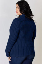 Woman wearing a navy ribbed sweater with long sleeves and dark blue jeans