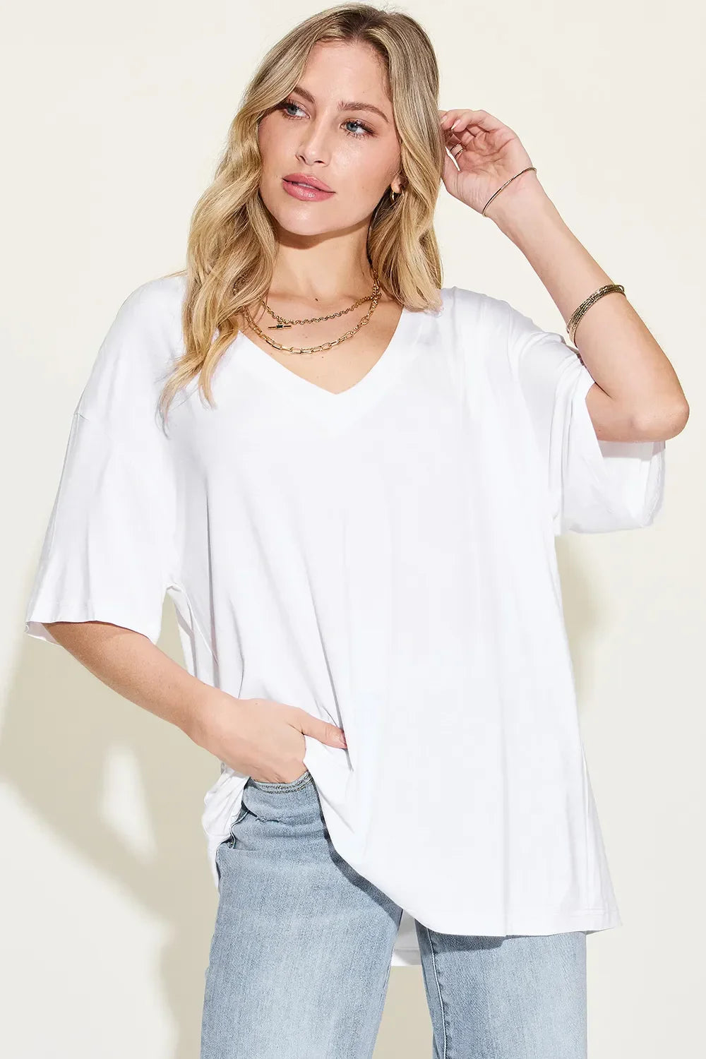 Woman in a loose white V-neck t-shirt and light blue jeans, casual fashion style