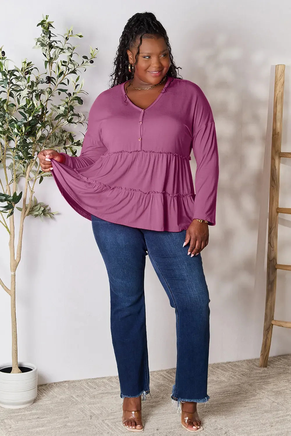 Woman wearing a mauve tiered long sleeve tunic top and blue jeans, plus size fashion