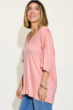 Woman wearing loose pink V-neck t-shirt and blue jeans, casual fashion outfit