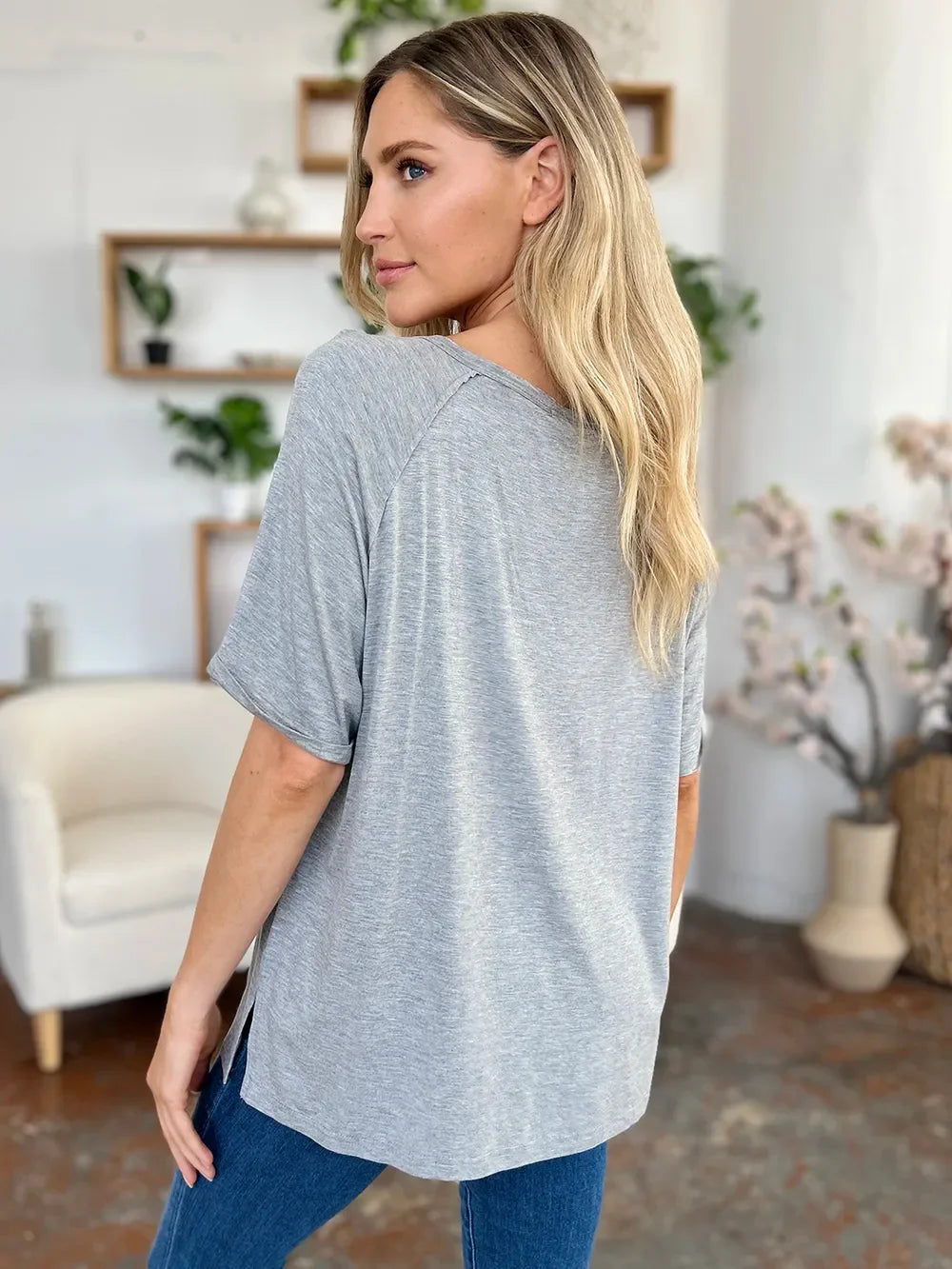 Woman wearing casual grey t-shirt and jeans in modern living room setting