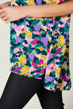 Woman wearing a colorful abstract floral print tunic top with black leggings
