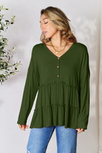 Woman wearing olive green ruffle long sleeve tunic top with jeans, layered gold necklace