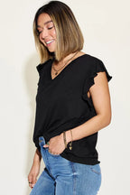 Woman wearing a black ruffle sleeve V-neck top and blue jeans, casual fashion style