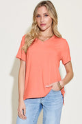 Woman wearing a coral V-neck short sleeve t-shirt and light blue jeans