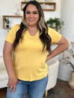 Smiling woman in yellow V-neck t-shirt and blue jeans standing in modern living room