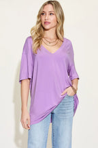 Woman wearing loose lavender V-neck t-shirt and light blue jeans on light background