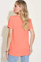 Woman wearing short sleeve coral t-shirt and light blue jeans, back view