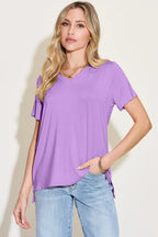 Woman wearing a casual lavender V-neck short sleeve top and light blue jeans.