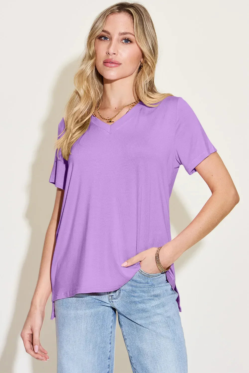Woman wearing a casual lavender V-neck short sleeve top and light blue jeans.