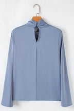 Light blue long sleeve blouse with back button details and keyhole opening, hanging on a hanger