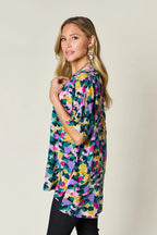 Woman wearing a colorful abstract floral print blouse and black pants