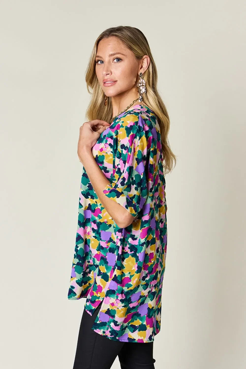 Woman wearing a colorful abstract floral print blouse and black pants