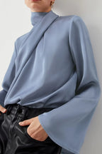 Woman wearing light blue satin blouse with flared sleeves and black leather pants